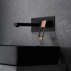 a black and gold wall mounted sink in a room with dark walls, grey flooring and stone steps