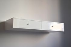 a white wall mounted shelf with two drawers