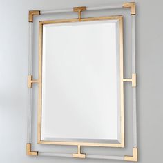 a mirror that is on the wall with some gold bars around it and a white background