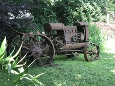 an old rusted out tractor sitting in the grass