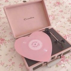 a pink record player sitting on top of a suitcase