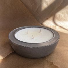 a white candle sitting on top of a piece of paper