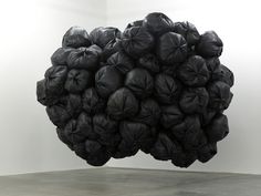 a large black object is suspended in the air over a concrete floor and wall, with white walls behind it