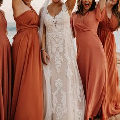 the bride and her bridesmaids pose for a photo on the beach in their dresses