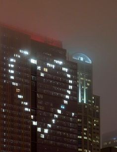 an airplane is flying in the air near some buildings at night time with lights shining on them