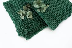 two pieces of green cloth with small flowers on top of each one, sitting on a white surface