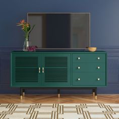 a green cabinet with two drawers and a large mirror on the top, in front of a blue wall