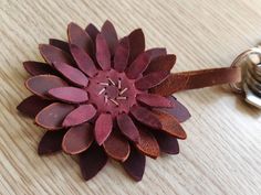 a leather flower on a wooden table next to a bottle opener