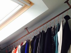 there are many different shirts hanging on the clothes rack in front of the skylight