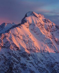 a large mountain covered in snow under a purple sky