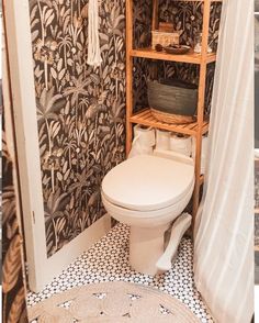 a white toilet sitting in a bathroom next to a wooden shelf filled with baskets and towels