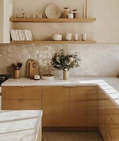 a kitchen with wooden cabinets and white counter tops, pots on the stove top and shelves above