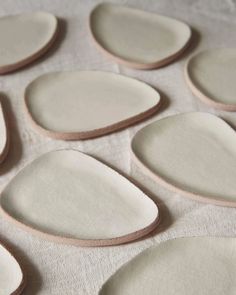 several pieces of white and brown pottery sitting on top of a tablecloth covered surface