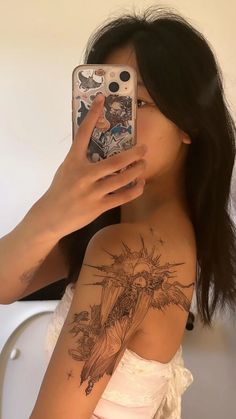 a woman taking a selfie in front of her mirror with tattoos on her arm