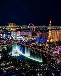 the las vegas strip is lit up at night with fountains and ferris wheel in the background