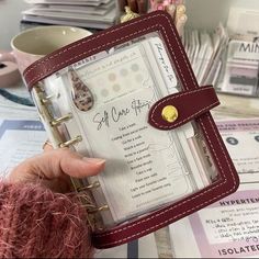 a person holding up a small book with writing on the pages and attached to it