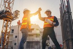 two men in safety vests and hard hats standing next to each other on construction site