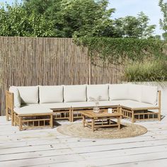 a couch and coffee table on a wooden deck in front of a bamboo privacy wall