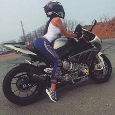 a woman sitting on top of a motorcycle in the middle of the road with her helmet on