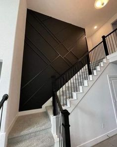 an empty staircase leading up to the second floor in a house with black walls and white railings