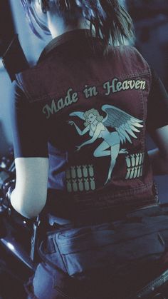 the back of a person on a motorcycle wearing a vest with an angel painted on it