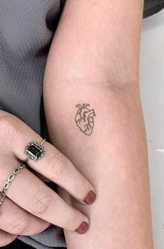 a woman's arm with a small heart tattoo on it