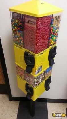 a large yellow box filled with candy on top of a black stand in front of a white wall