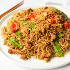 a white plate topped with meat and veggies next to chopsticks on a table