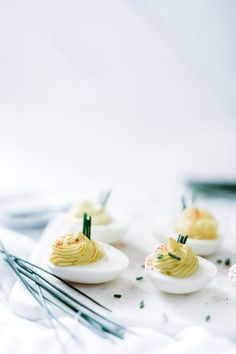 small deviled eggs with mustard and chives on a white plate, ready to be eaten