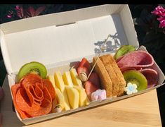 a box filled with assorted fruits and meats on top of a wooden table