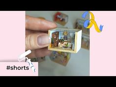 someone is holding up a miniature house in their hand, with the door open to show what's inside