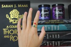 a person's hand with a ring on it next to some books and other items