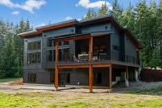 a large gray house sitting in the middle of a forest