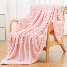 a pink blanket sitting on top of a wooden chair