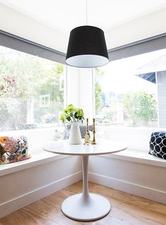 a white table sitting in front of a window next to a vase filled with flowers