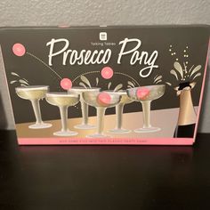 a pink box with three champagne glasses in it on a black table next to a white wall