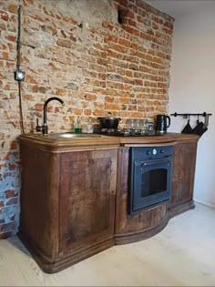 a kitchen with an oven, sink and brick wall