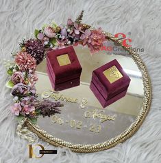 a mirror with two boxes sitting on it's side and flowers around the edge