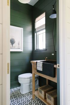 an instagram photo of a bathroom with dark green walls and white tile flooring