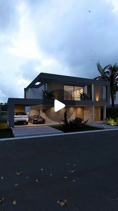 a modern house is lit up at night with the lights on and cars parked in front