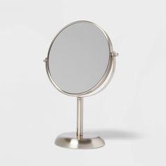 a round mirror on a metal stand against a white background with no one in it