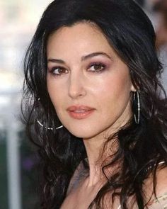 a close up of a person with long black hair and wearing large silver hoop earrings