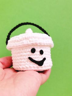 a small crocheted basket with a smiling face on it's side, held in someones hand