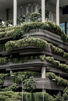 an unusual building with plants growing on the side of it's sides and columns