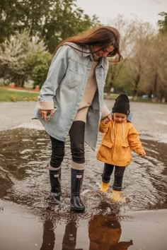 a woman and child are walking in the rain together, one is holding her hand