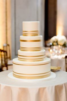 a white and gold wedding cake sitting on top of a table