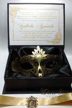 a black and gold masquerade mask in a gift box with a golden ribbon