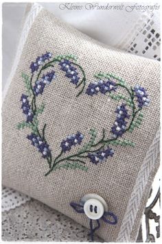 a heart shaped pillow with blue flowers on it and a white lace doily next to it