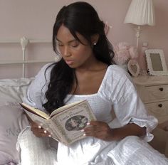 a woman sitting on a bed reading a book