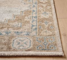 a beige rug with blue and white designs on the top is laying on a wooden floor